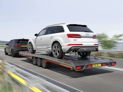 Family SUV loaded on an open trailer transporter on a UK road